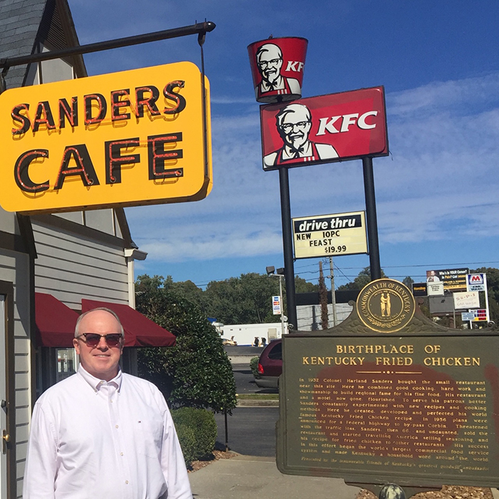 Man in front of a sign reading "Sanders Cafe"